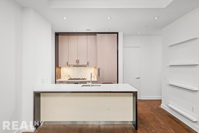 261 W 25th St Unit 8A, New York City, NY 10001 - kitchen with a sink, dark wood-style flooring, light countertops, a peninsula, and backsplash