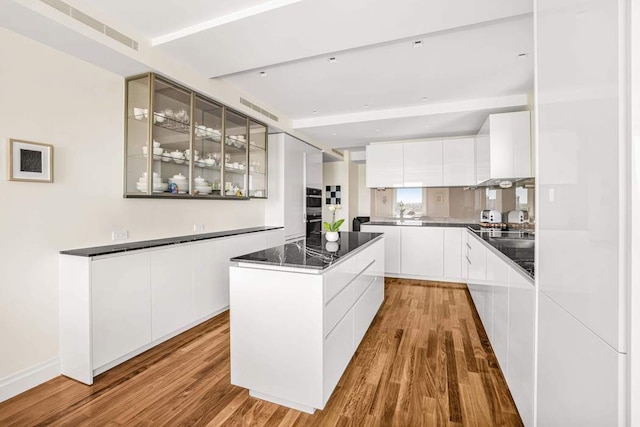 25 E End Ave Unit 10E, New York City, NY 10075 - kitchen with modern cabinets, glass insert cabinets, light wood-type flooring, a kitchen island, and white cabinets