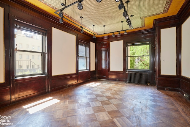 4 E 82nd St Unit 3R, New York City, NY 10028 - empty room with radiator heating unit, rail lighting, ornamental molding, wood walls, and a wainscoted wall