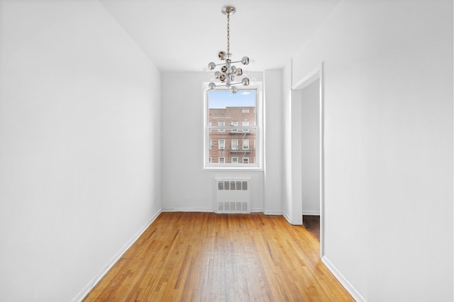 400 E 17th St Unit 608, New York City, NY 11226 - unfurnished dining area with radiator, a chandelier, light wood-style flooring, and baseboards