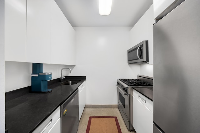 99 John St Unit 524, New York City, NY 10038 - kitchen featuring appliances with stainless steel finishes, a sink, white cabinets, dark countertops, and baseboards