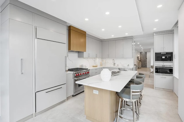 422 E 72nd St Unit 37Ad, New York City, NY 10021 - kitchen with luxury stove, a sink, a center island, a breakfast bar, and recessed lighting