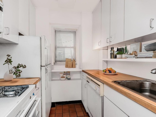 333 E 66th St Unit 12-C, New York City, NY 10065 - kitchen with white dishwasher, a sink, white cabinets, dark tile patterned flooring, and butcher block countertops