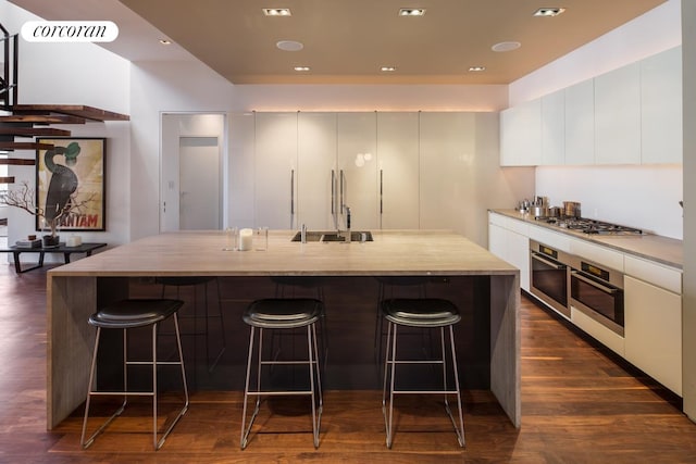 345 W 13th St Unit Ph6B, New York City, NY 10014 - kitchen with appliances with stainless steel finishes, a sink, modern cabinets, dark wood-style flooring, and a breakfast bar area
