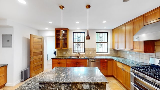 93A Rutland Rd, New York City, NY 11225 - kitchen with stainless steel appliances, electric panel, wall chimney range hood, radiator heating unit, and dark stone counters
