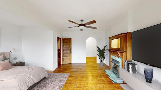93A Rutland Rd, New York City, NY 11225 - bedroom featuring arched walkways, a fireplace with flush hearth, light wood-style flooring, and a ceiling fan