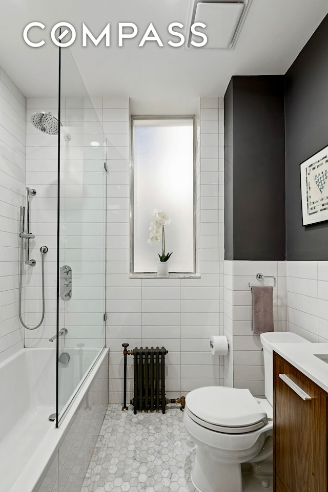 40 W 67th St Unit 1A, New York City, NY 10023 - bathroom with tiled shower / bath combo, toilet, vanity, tile walls, and radiator
