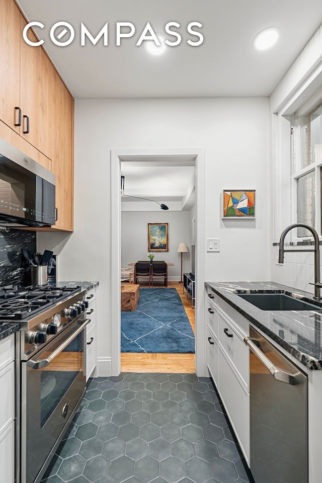 40 W 67th St Unit 1A, New York City, NY 10023 - kitchen with stainless steel appliances, a sink, dark stone countertops, and dark tile patterned flooring