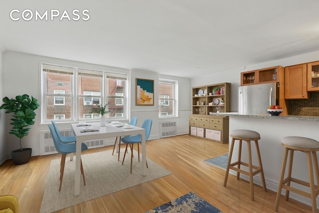 400 E 17th St Unit 711, New York City, NY 11226 - dining room featuring radiator heating unit, light wood-style floors, and a desk