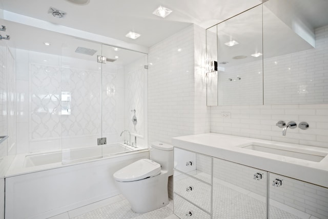 116 E 66th St Unit 9/10C, New York City, NY 10065 - full bathroom with tile walls, toilet, combined bath / shower with glass door, tile patterned floors, and vanity