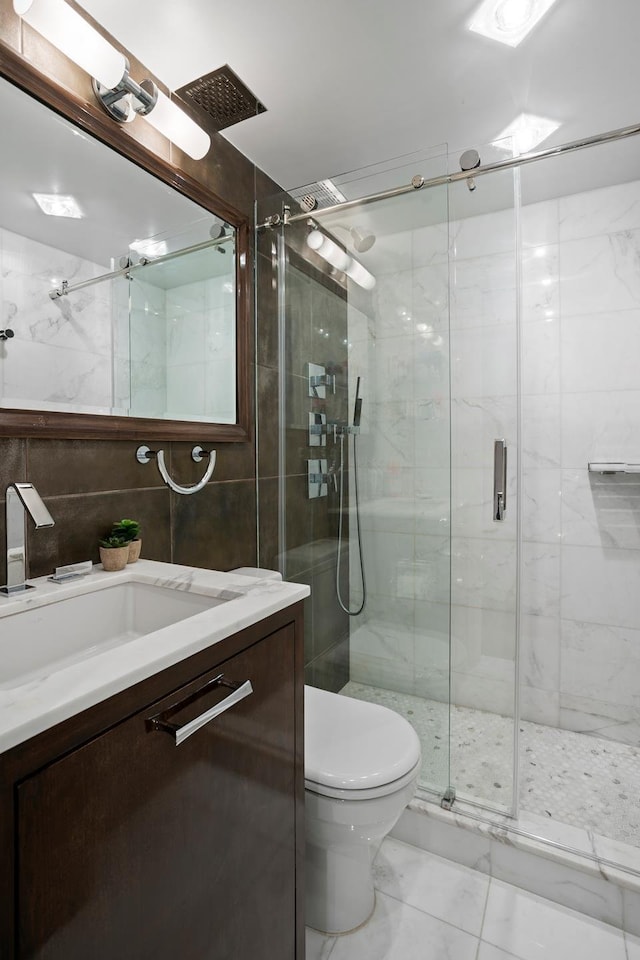 116 E 66th St Unit 9/10C, New York City, NY 10065 - bathroom featuring vanity, tile walls, marble look tile flooring, a stall shower, and toilet