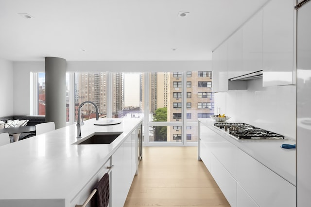 1355 1st Ave Unit 11Fl, New York City, NY 10021 - kitchen featuring a sink, modern cabinets, stainless steel gas cooktop, and white cabinetry