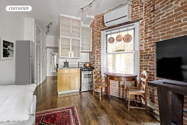 77 Perry St Unit 4C, New York City, NY 10014 - kitchen with stainless steel range with gas stovetop, a wall unit AC, dark wood finished floors, stainless steel counters, and rail lighting