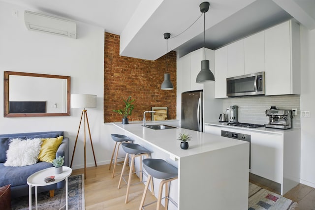 43 Halsey St Unit 4, New York City, NY 11216 - kitchen with appliances with stainless steel finishes, a sink, a wall mounted air conditioner, a breakfast bar area, and light wood-type flooring