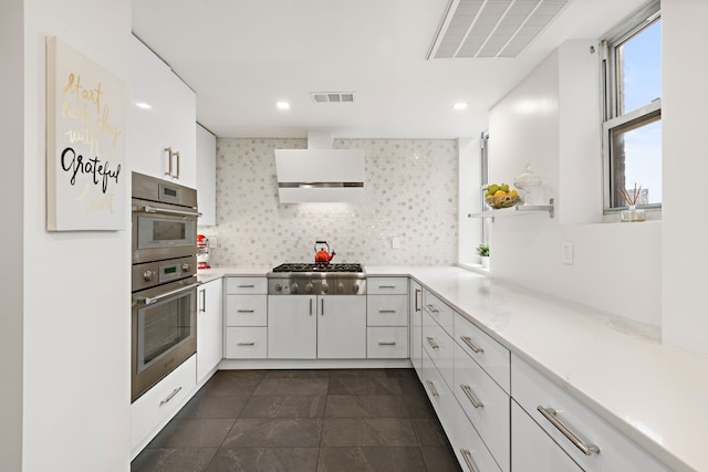 10 W 86th St Unit 15A, New York City, NY 10024 - kitchen featuring appliances with stainless steel finishes, range hood, white cabinetry, light countertops, and recessed lighting