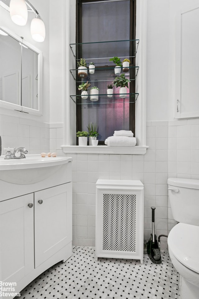 354 Baltic St Unit 2, New York City, NY 11201 - half bathroom featuring tile walls, vanity, radiator heating unit, toilet, and wainscoting