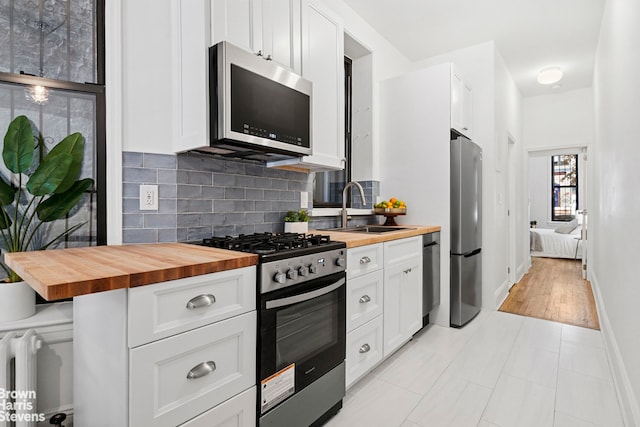 354 Baltic St Unit 2, New York City, NY 11201 - kitchen with butcher block counters, stainless steel appliances, a sink, decorative backsplash, and radiator heating unit