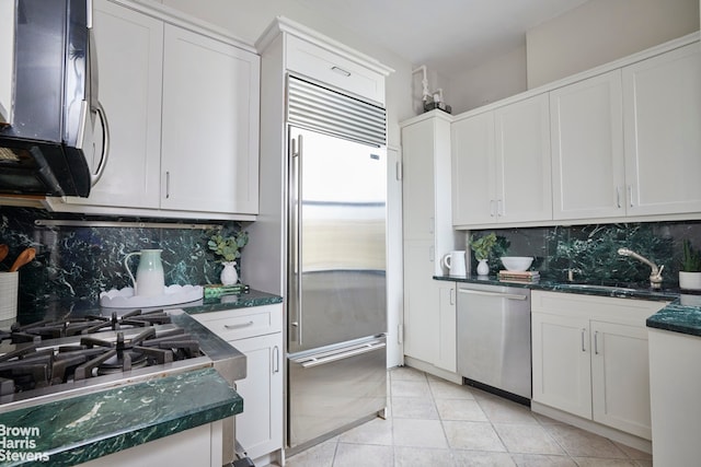 970 Park Ave Unit 8N, New York City, NY 10028 - kitchen featuring stainless steel appliances, backsplash, white cabinets, and dark stone countertops