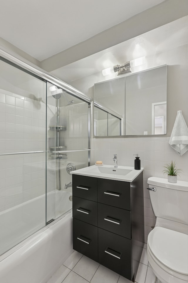 315 E 70th St Unit 9A, New York City, NY 10021 - bathroom with toilet, vanity, shower / bath combination with glass door, tile patterned flooring, and tile walls