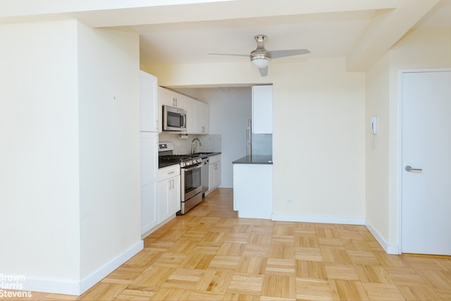 249 E 48th St Unit 3A, New York City, NY 10017 - kitchen featuring stainless steel appliances, baseboards, backsplash, and a ceiling fan
