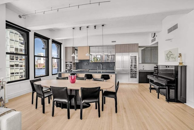 30 Main St Unit 11F, New York City, NY 11201 - dining space with light wood-style flooring, baseboards, and rail lighting