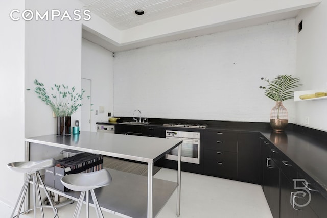 100 Wooster St Unit 4, New York City, NY 10012 - kitchen with oven, dark cabinetry, a sink, and gas stovetop