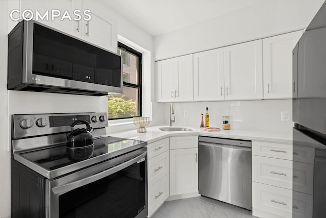 234 E 35th St Unit 3, New York City, NY 10016 - kitchen featuring stainless steel appliances, a sink, light countertops, light marble finish floors, and white cabinetry