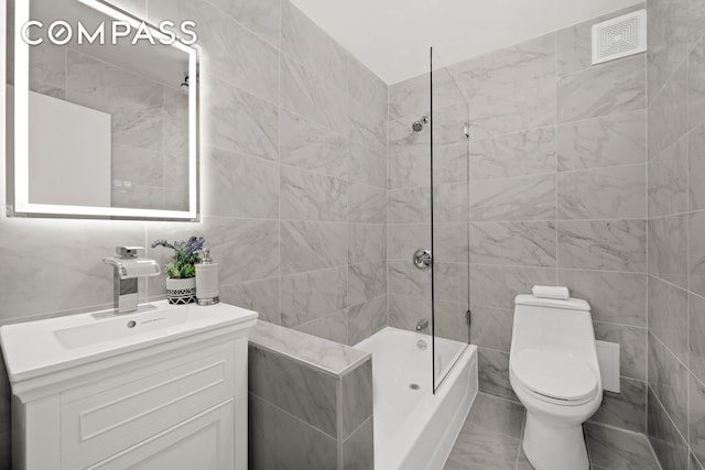 234 E 35th St Unit 3, New York City, NY 10016 - bathroom with tile walls, vanity, toilet, bathing tub / shower combination, and marble look tiles