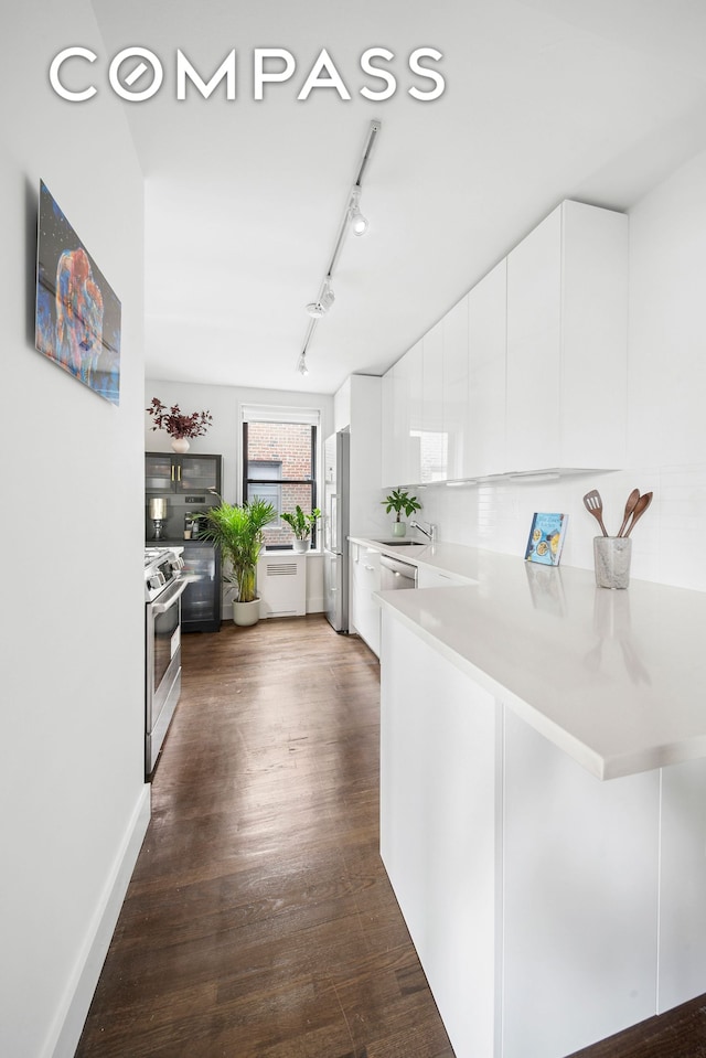 9511 Shore Rd Unit 505, New York City, NY 11209 - kitchen featuring appliances with stainless steel finishes, light countertops, white cabinets, dark wood-style flooring, and a peninsula