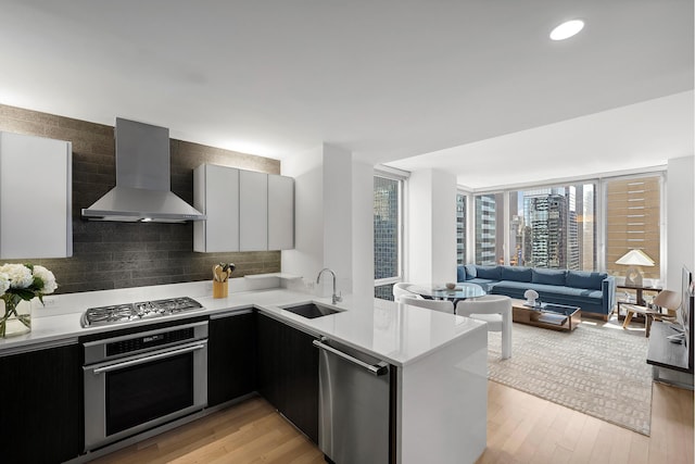 247 W 46th St Unit 3505, New York City, NY 10036 - kitchen with appliances with stainless steel finishes, wall chimney range hood, light countertops, light wood-type flooring, and modern cabinets