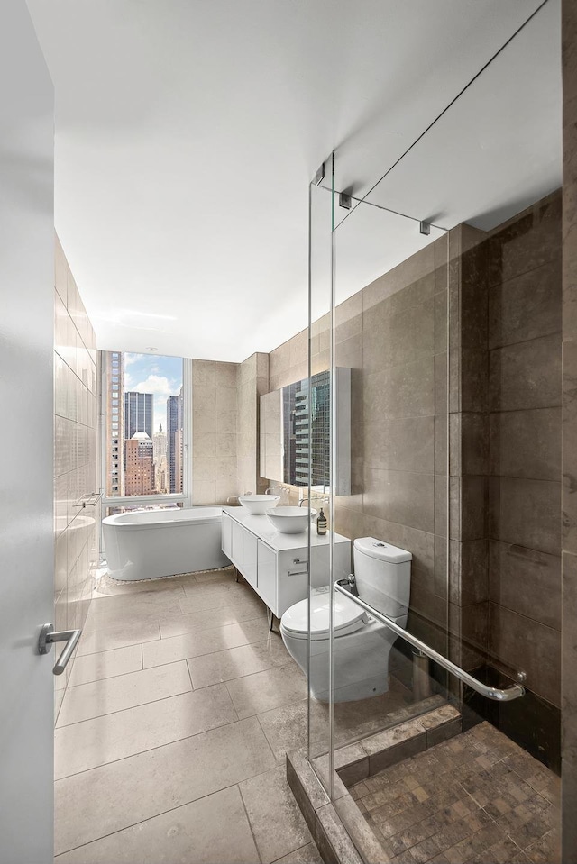 247 W 46th St Unit 3505, New York City, NY 10036 - full bath featuring double vanity, tile walls, a soaking tub, a shower stall, and tile patterned flooring