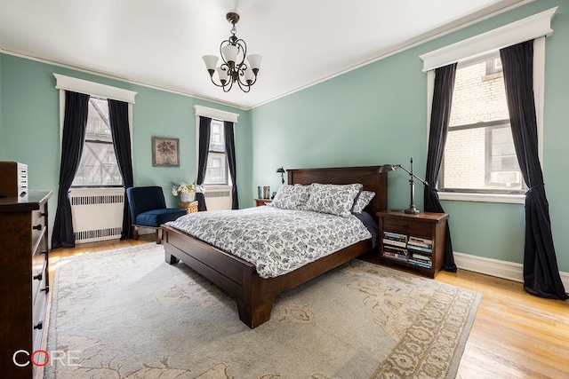 35-15 84th St Unit 4A, New York City, NY 11372 - bedroom featuring radiator, crown molding, multiple windows, wood finished floors, and a chandelier