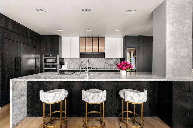 11 Beach St Unit 5B, New York City, NY 10013 - kitchen with modern cabinets, light wood finished floors, light stone countertops, a sink, and tasteful backsplash