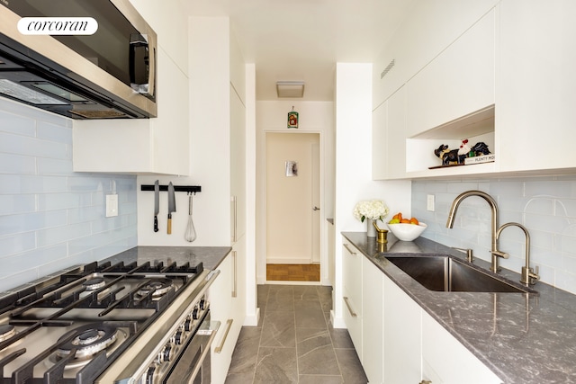 155 E 34th St Unit 8S, New York City, NY 10016 - kitchen featuring appliances with stainless steel finishes, white cabinets, dark stone counters, and backsplash