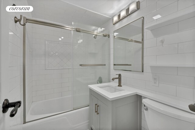 200 E 58th St Unit 5E, New York City, NY 10022 - full bath featuring vanity, bath / shower combo with glass door, tile walls, and decorative backsplash
