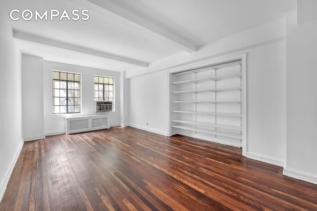 320 E 42nd St Unit 516, New York City, NY 10017 - spare room featuring radiator heating unit, wood-type flooring, beam ceiling, cooling unit, and built in shelves