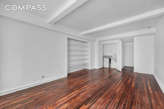 320 E 42nd St Unit 516, New York City, NY 10017 - unfurnished living room featuring beamed ceiling, hardwood / wood-style flooring, and built in shelves