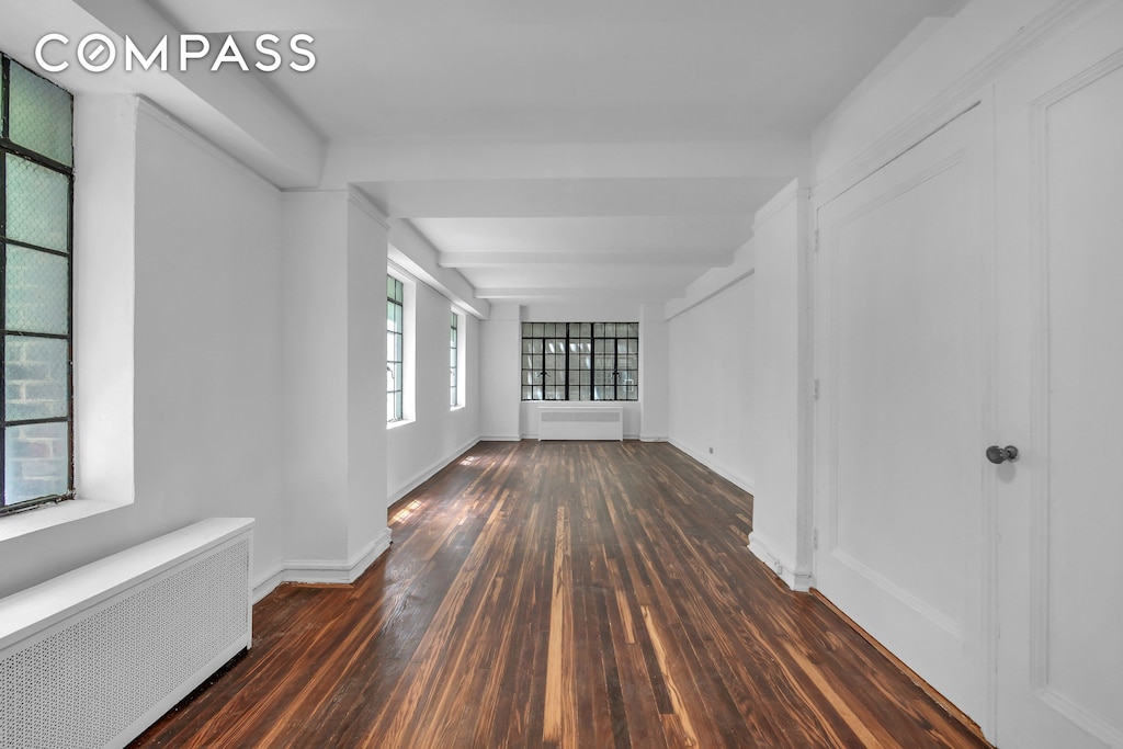 320 E 42nd St Unit 418, New York City, NY 10017 - empty room featuring radiator heating unit and hardwood / wood-style floors