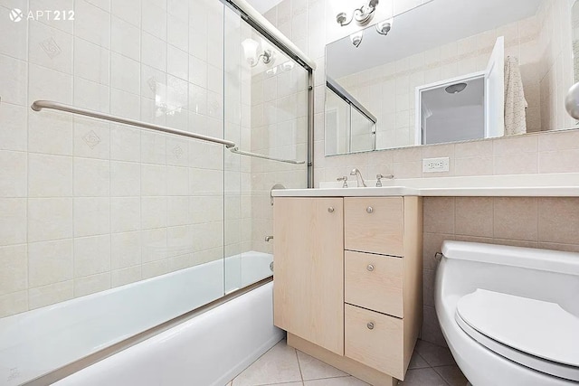 340 E 80th St Unit 20-J, New York City, NY 10075 - bathroom with tile walls, tile patterned flooring, enclosed tub / shower combo, toilet, and vanity