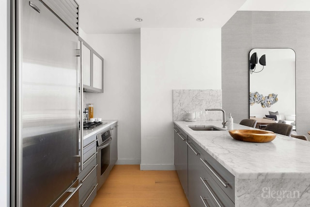 210 Lafayette St Unit 5A, New York City, NY 10012 - kitchen with stainless steel appliances, a peninsula, gray cabinets, a sink, and light wood finished floors
