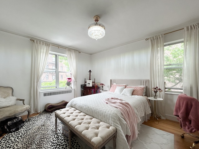 100 Bennett Ave Unit 4B, New York City, NY 10033 - bedroom featuring radiator heating unit, wood finished floors, and a chandelier