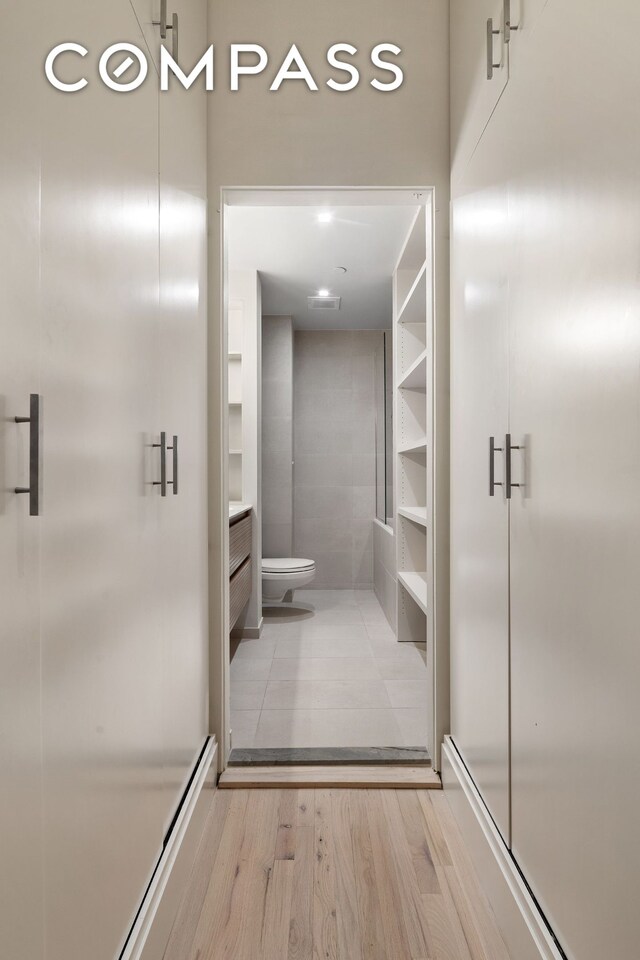 28 W 38th St Unit 6E, New York City, NY 10018 - full bath featuring a stall shower, wood finished floors, and toilet