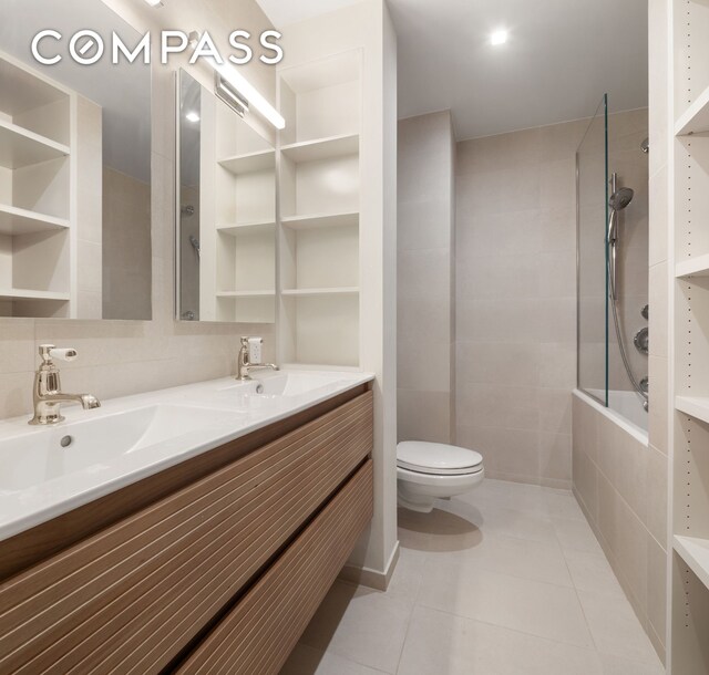 28 W 38th St Unit 6E, New York City, NY 10018 - bathroom featuring tile patterned floors, toilet, double vanity, and tiled shower / bath combo
