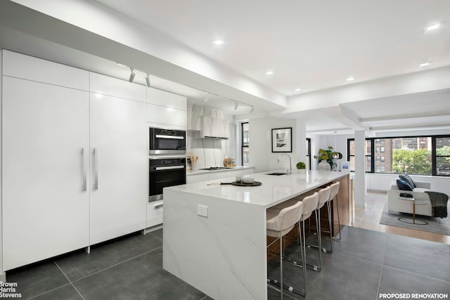 230 E 73rd St Unit 8Def, New York City, NY 10021 - kitchen featuring oven, a sink, modern cabinets, white cabinetry, and a kitchen bar
