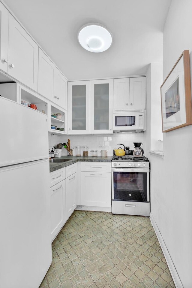 357 W End Ave Unit 2, New York City, NY 10024 - kitchen featuring white appliances, white cabinetry, light flooring, dark countertops, and glass insert cabinets