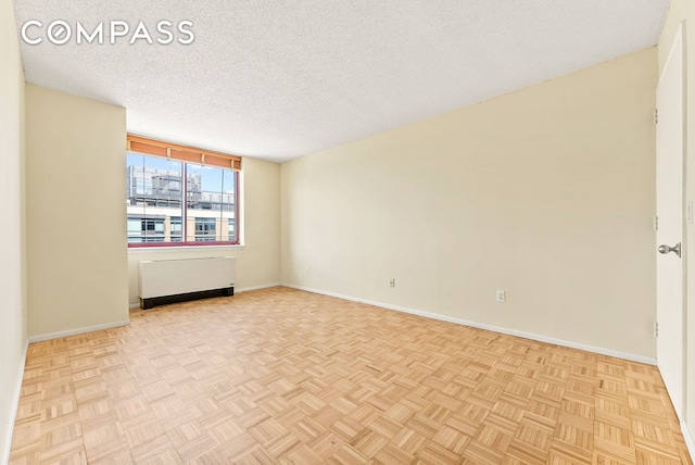 4-74 48th Ave Unit Ph2B, New York City, NY 11109 - unfurnished room featuring radiator heating unit, baseboards, and a textured ceiling
