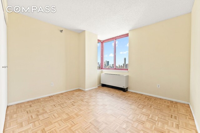 4-74 48th Ave Unit Ph2B, New York City, NY 11109 - spare room with baseboards, a textured ceiling, and a view of skyline