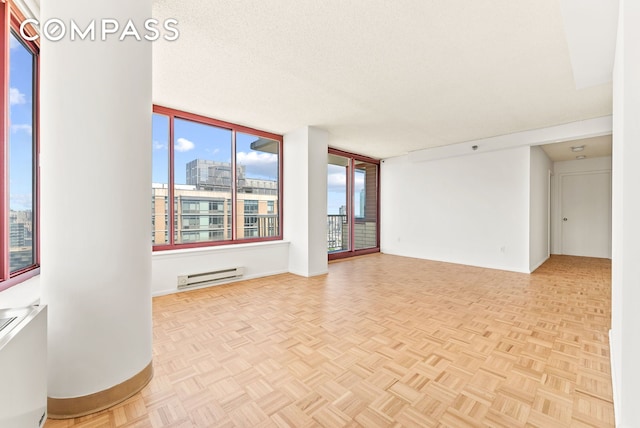 4-74 48th Ave Unit Ph2B, New York City, NY 11109 - empty room featuring a baseboard radiator, healthy amount of natural light, a city view, and baseboards