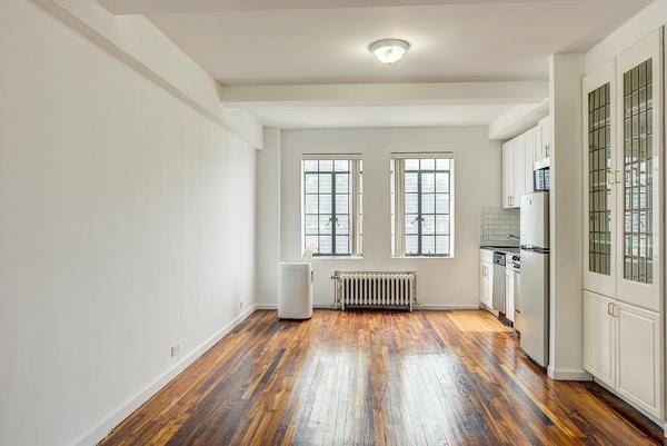 45 Tudor City Pl Unit 2002, New York City, NY 10017 - kitchen with radiator, stainless steel appliances, hardwood / wood-style flooring, white cabinets, and baseboards