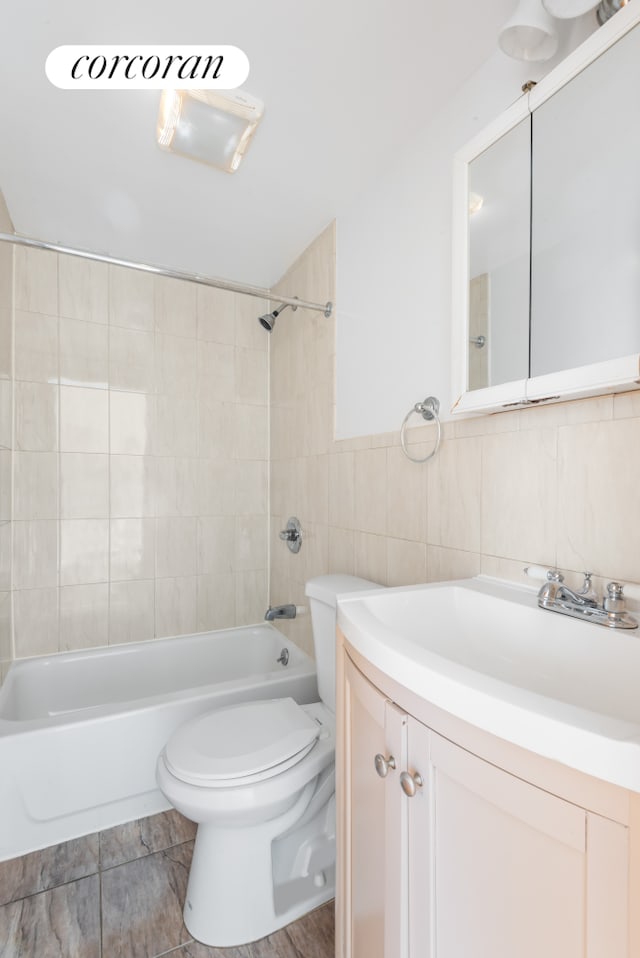 238 26th St, New York City, NY 11232 - bathroom featuring vanity, toilet, shower / tub combination, and tile walls